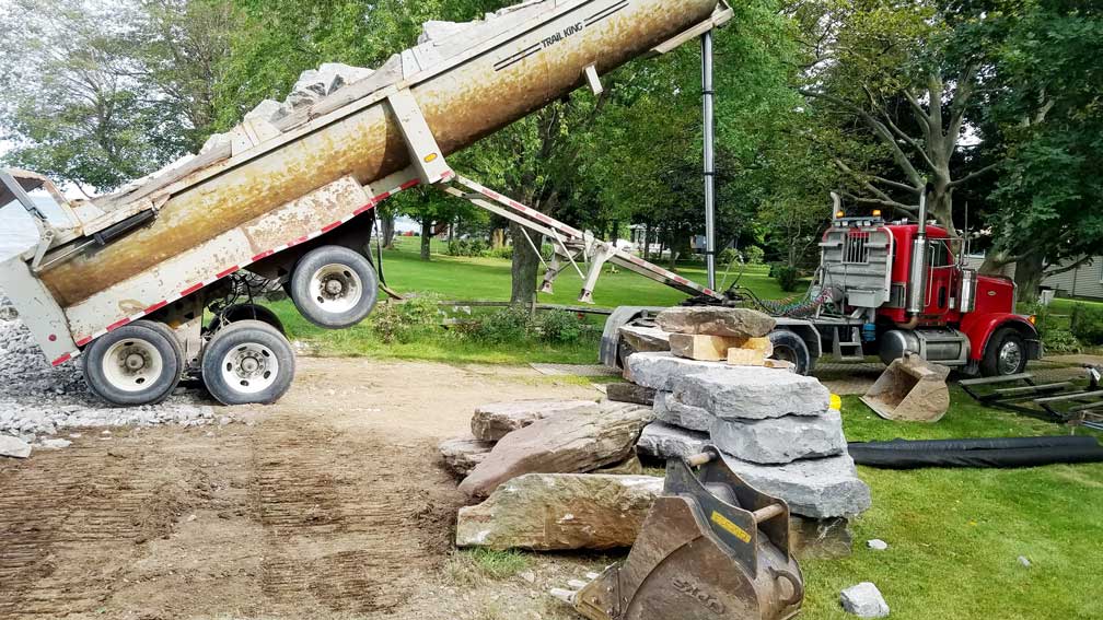 truck-dumping-stone Dump truck dumping stone at a construction site